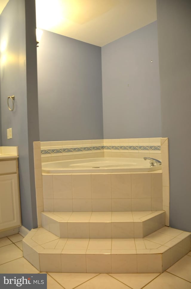 bathroom featuring tiled tub, tile patterned flooring, and vanity