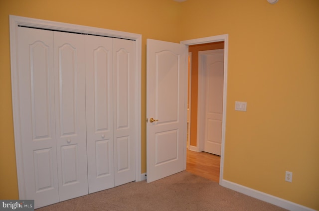 unfurnished bedroom featuring light colored carpet and a closet