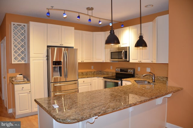 kitchen with kitchen peninsula, sink, white cabinets, and stainless steel appliances