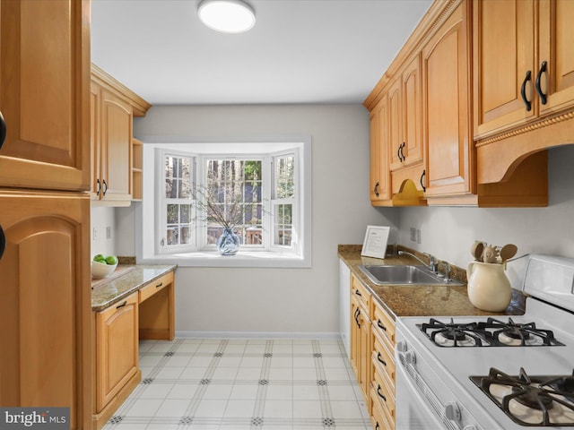 kitchen featuring white range with gas cooktop, light floors, baseboards, and a sink