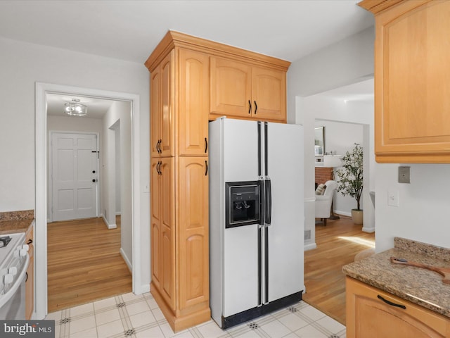 kitchen featuring light brown cabinets, stone counters, light floors, and white appliances