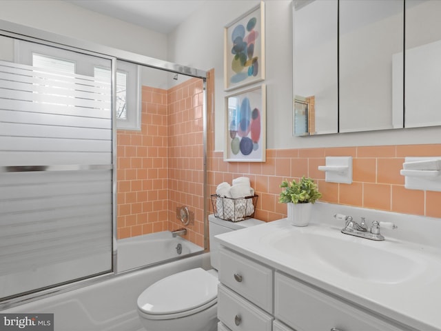 full bathroom with enclosed tub / shower combo, toilet, tile walls, and vanity