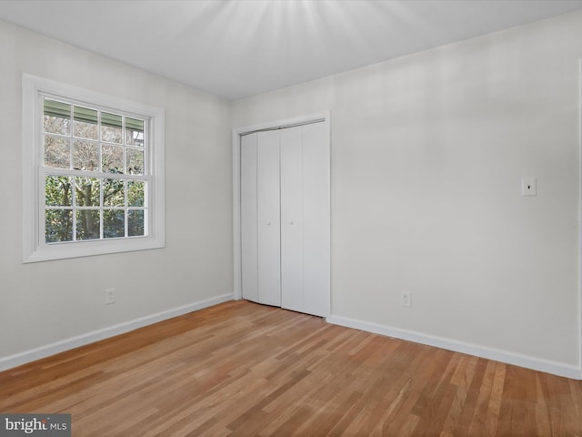 unfurnished bedroom featuring a closet, baseboards, and wood finished floors