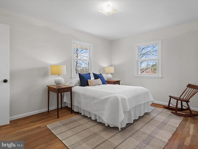 bedroom with hardwood / wood-style floors, multiple windows, and baseboards