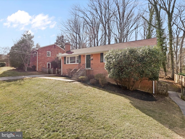 view of front of house featuring a front yard, fence, brick siding, and a chimney