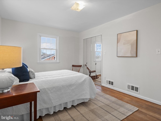 bedroom with visible vents, multiple windows, baseboards, and wood finished floors