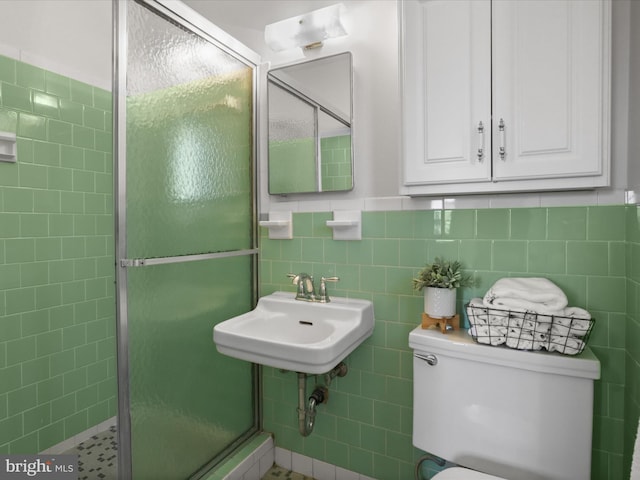 full bath with a sink, a shower stall, wainscoting, tile walls, and toilet