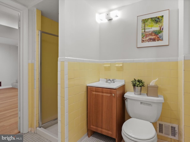 bathroom with visible vents, toilet, tile walls, and a shower stall