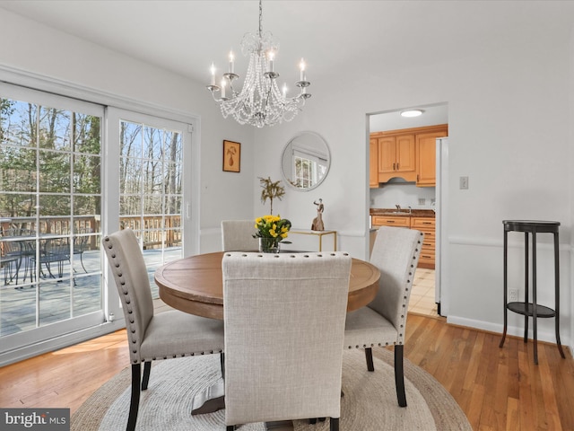 dining room featuring baseboards, an inviting chandelier, and light wood finished floors