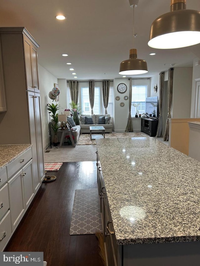 kitchen with white cabinets, light stone counters, a kitchen island, and dark hardwood / wood-style floors