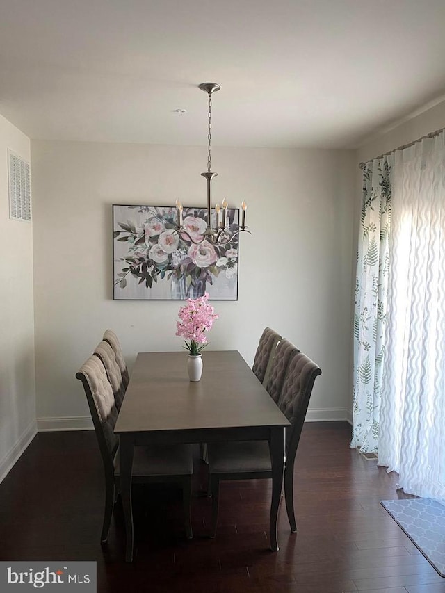 dining space featuring dark hardwood / wood-style floors and a chandelier