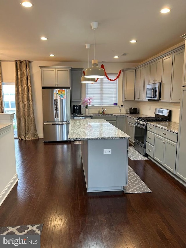 kitchen with gray cabinetry, light stone countertops, dark hardwood / wood-style flooring, pendant lighting, and appliances with stainless steel finishes