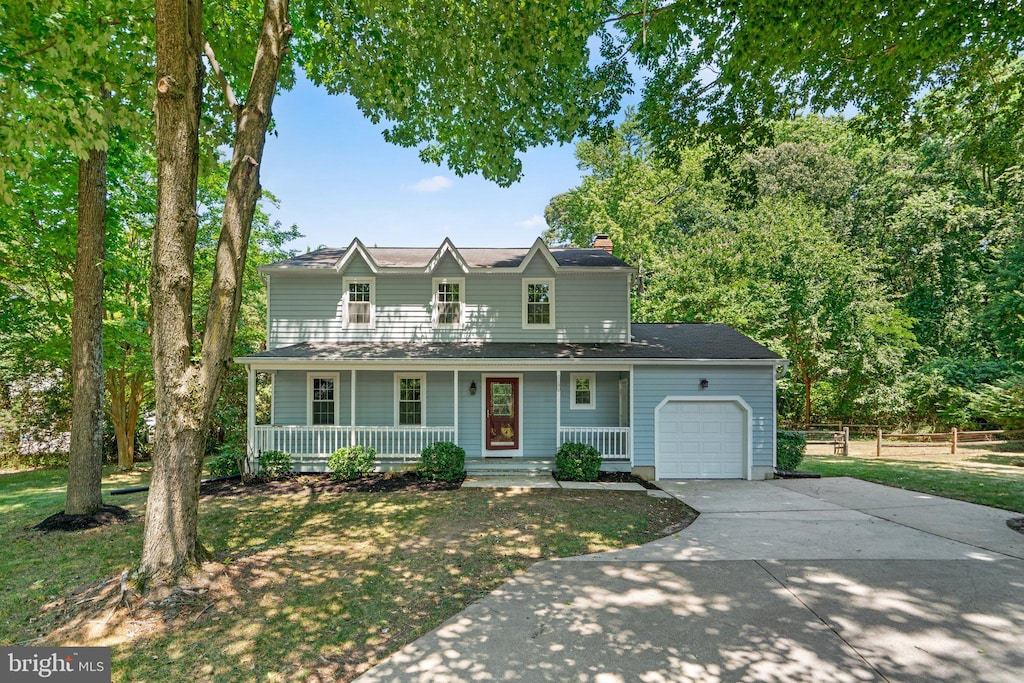 view of property featuring a front yard, a porch, and a garage