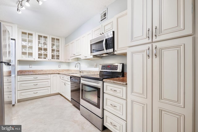 kitchen with white cabinets, sink, light stone countertops, a textured ceiling, and stainless steel appliances