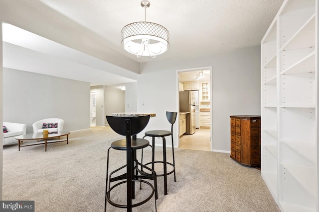 dining room with light carpet and a textured ceiling