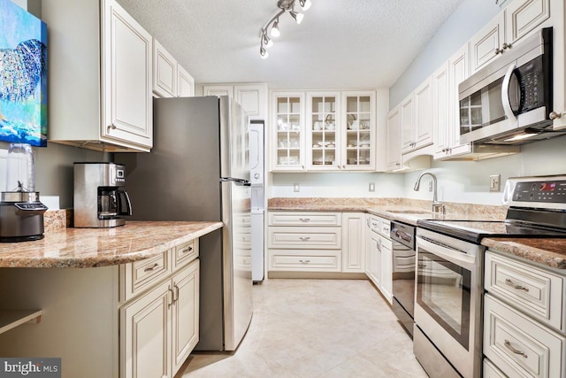 kitchen featuring white cabinets, appliances with stainless steel finishes, a textured ceiling, and light stone countertops