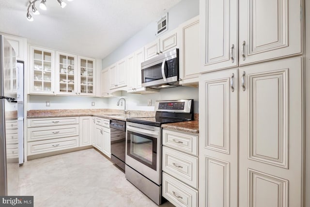 kitchen with sink, light stone countertops, a textured ceiling, appliances with stainless steel finishes, and white cabinetry