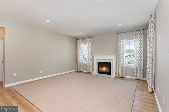 unfurnished living room featuring light wood-type flooring and a premium fireplace