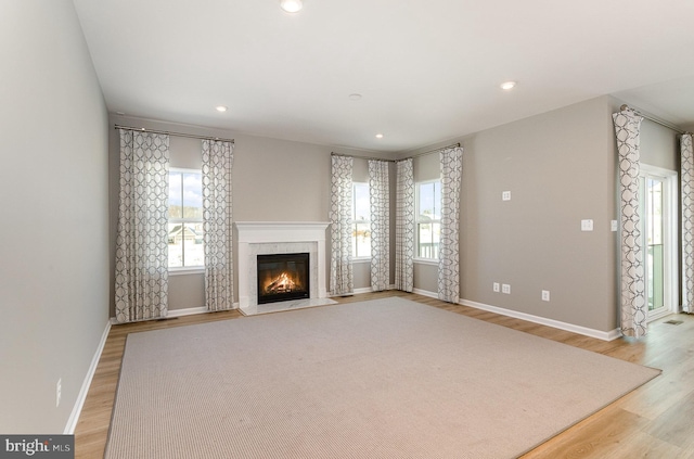 unfurnished living room with a high end fireplace and light hardwood / wood-style floors