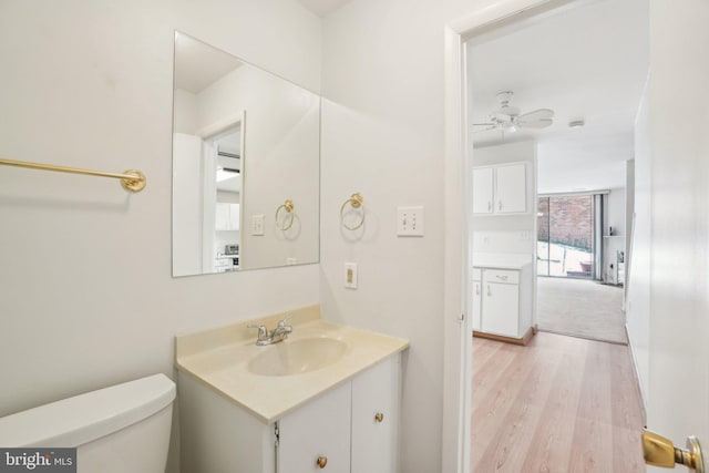 bathroom featuring wood-type flooring, vanity, toilet, and ceiling fan