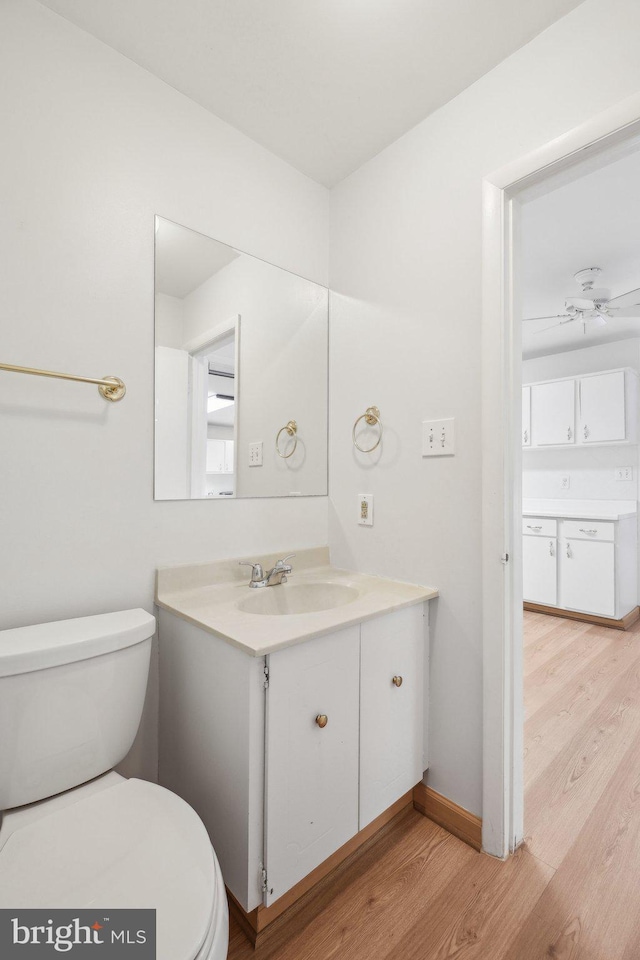 bathroom with hardwood / wood-style flooring, vanity, ceiling fan, and toilet