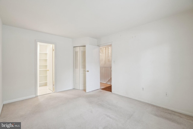 unfurnished bedroom featuring light colored carpet and a spacious closet