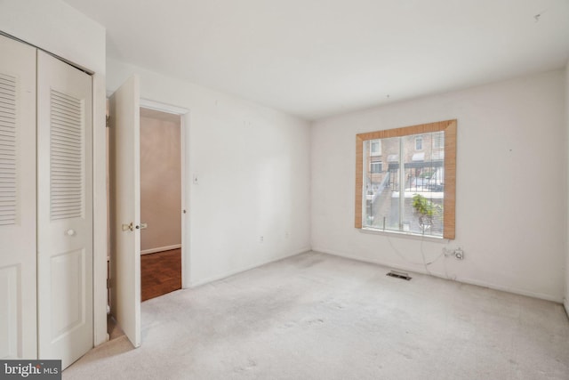 unfurnished bedroom with light carpet and a closet