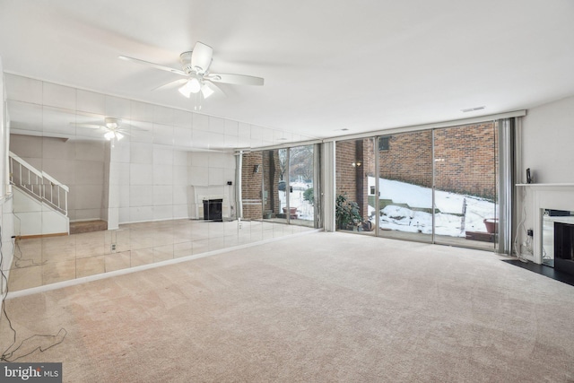 unfurnished living room featuring carpet flooring, ceiling fan, and a wall of windows