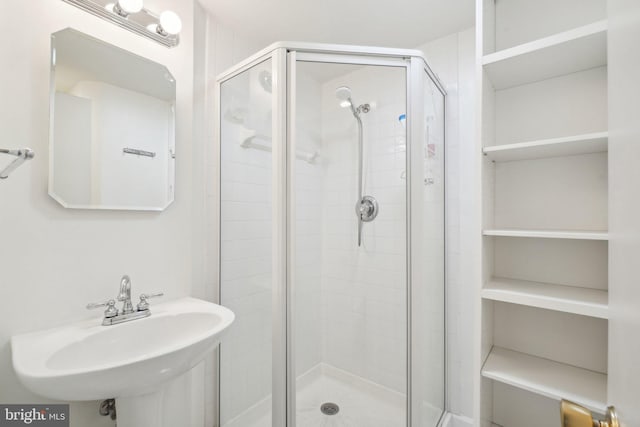 bathroom with a shower with shower door and sink