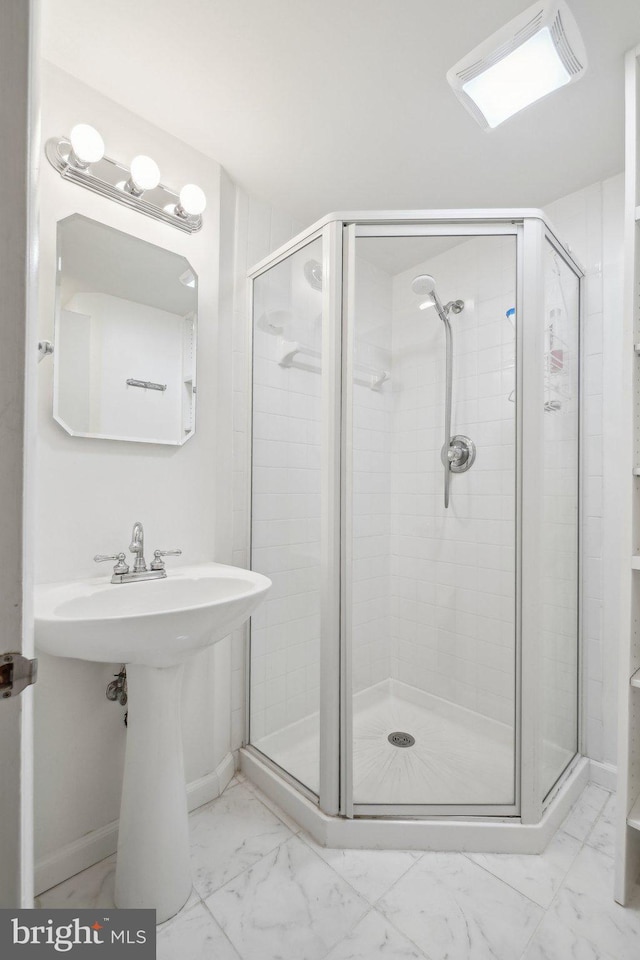 bathroom featuring a shower with door and sink