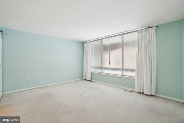 unfurnished room with a barn door and light colored carpet