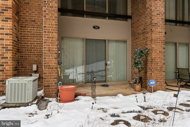 snow covered property entrance featuring central air condition unit