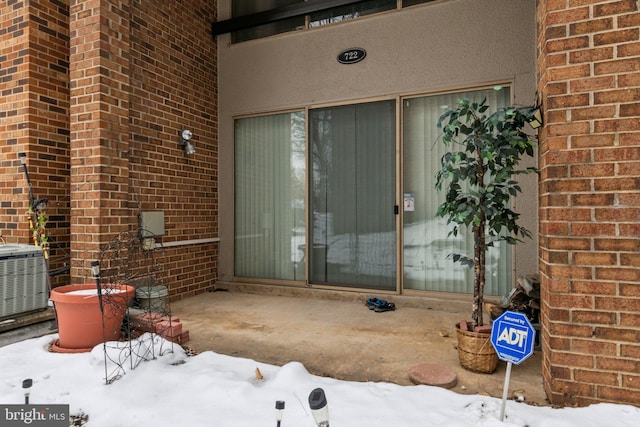 snow covered property entrance featuring central AC unit