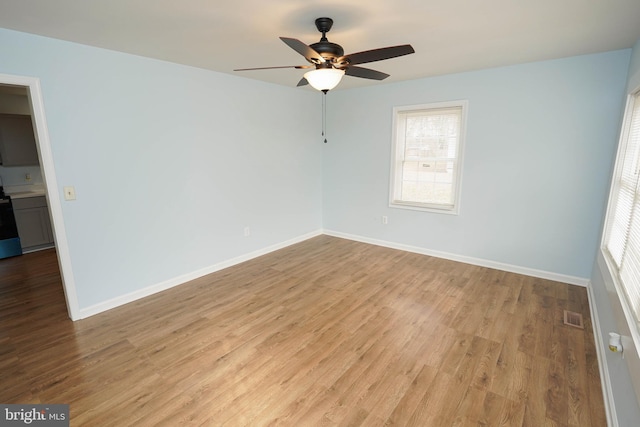 empty room with ceiling fan, light hardwood / wood-style floors, and a healthy amount of sunlight