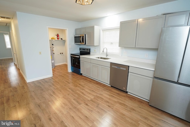 kitchen featuring stainless steel appliances, light hardwood / wood-style flooring, a healthy amount of sunlight, and sink