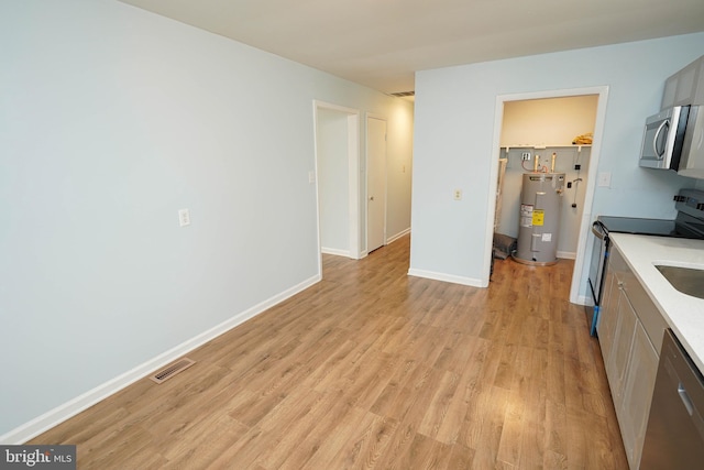 kitchen with electric water heater, stainless steel appliances, light hardwood / wood-style flooring, and gray cabinetry