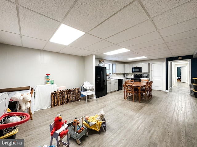 dining area with light hardwood / wood-style flooring, a drop ceiling, and sink