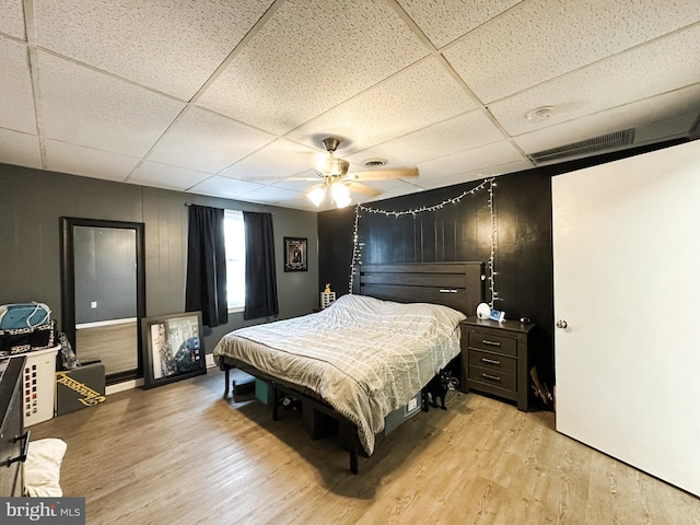 bedroom with a paneled ceiling, light hardwood / wood-style flooring, and ceiling fan