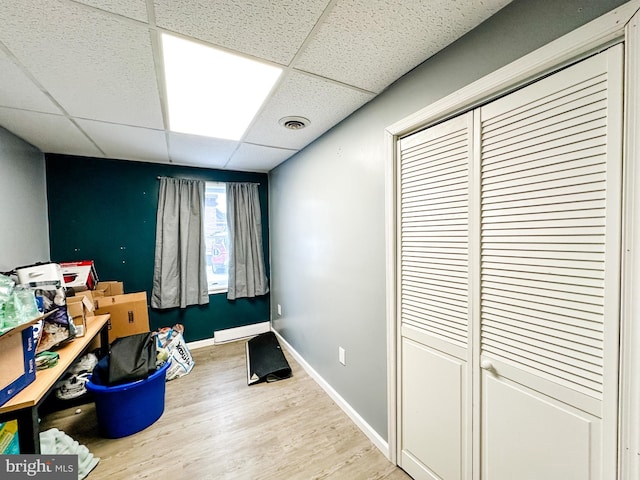 interior space featuring a paneled ceiling, wood-type flooring, and baseboard heating