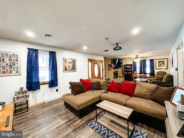 living room featuring hardwood / wood-style floors, a brick fireplace, plenty of natural light, and ceiling fan