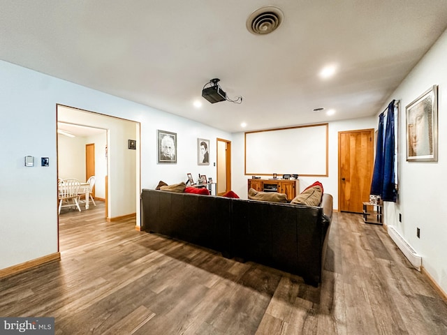 cinema room with a baseboard heating unit and hardwood / wood-style flooring