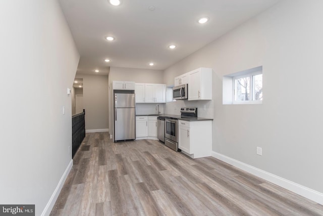 kitchen featuring sink, decorative backsplash, light hardwood / wood-style floors, white cabinetry, and stainless steel appliances