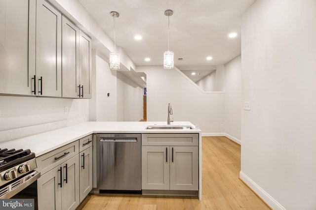 kitchen with sink, stainless steel appliances, kitchen peninsula, pendant lighting, and gray cabinets