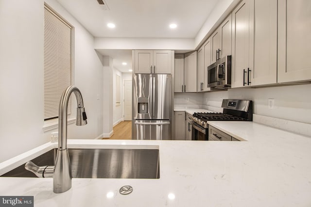 kitchen featuring gray cabinets, sink, stainless steel appliances, and light hardwood / wood-style flooring