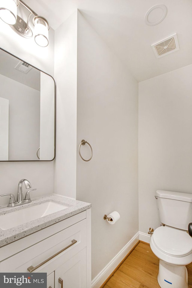 bathroom with hardwood / wood-style flooring, vanity, and toilet