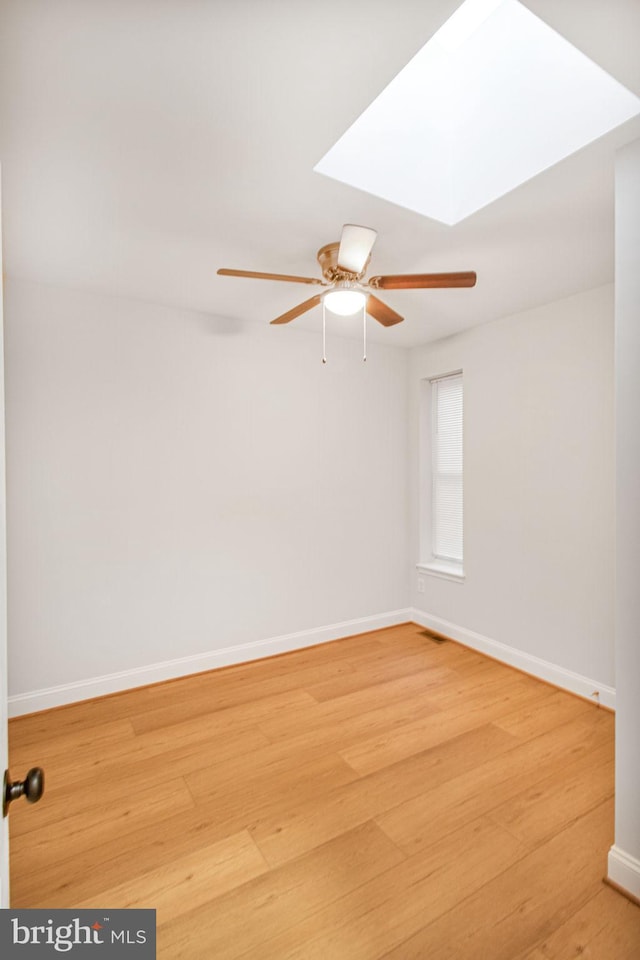 spare room with a skylight, ceiling fan, and wood-type flooring