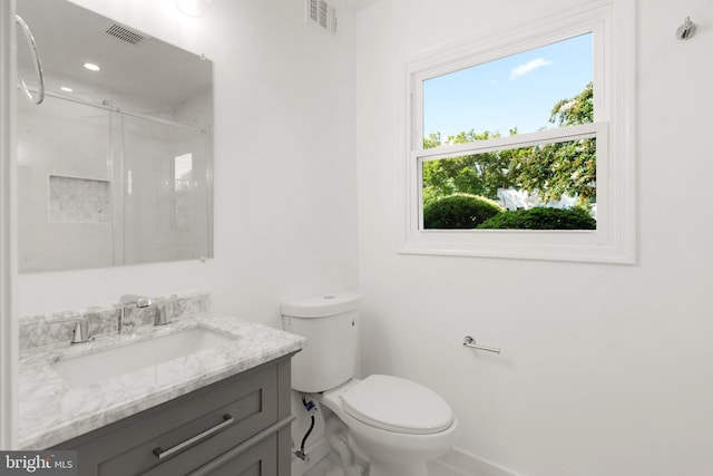 bathroom with toilet, vanity, and walk in shower