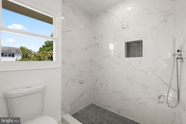 bathroom with a tile shower and toilet