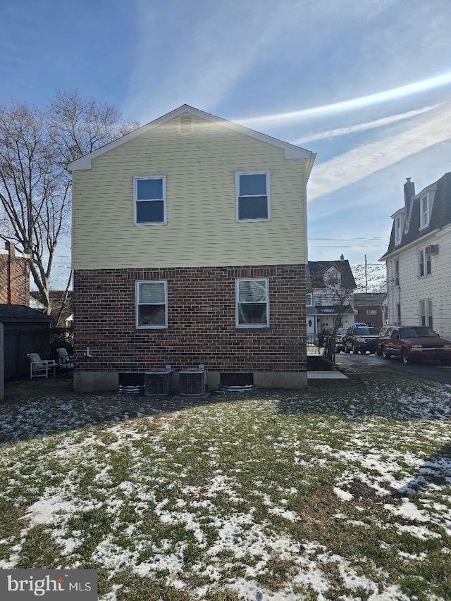 snow covered property with a lawn and central AC unit