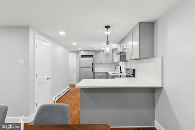 kitchen featuring tasteful backsplash, a baseboard heating unit, pendant lighting, fridge, and gray cabinets